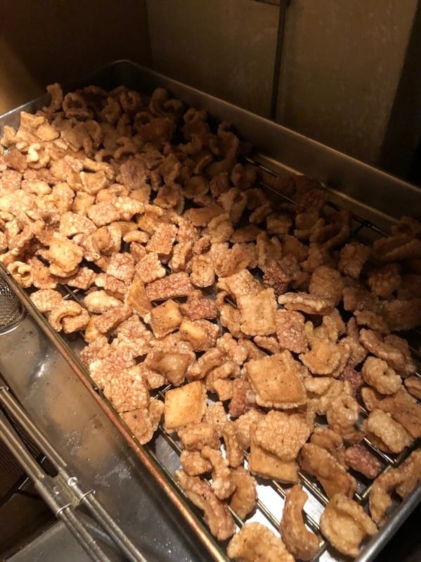 揚げたてのポークスクラッチングスをバットに並べたところ。